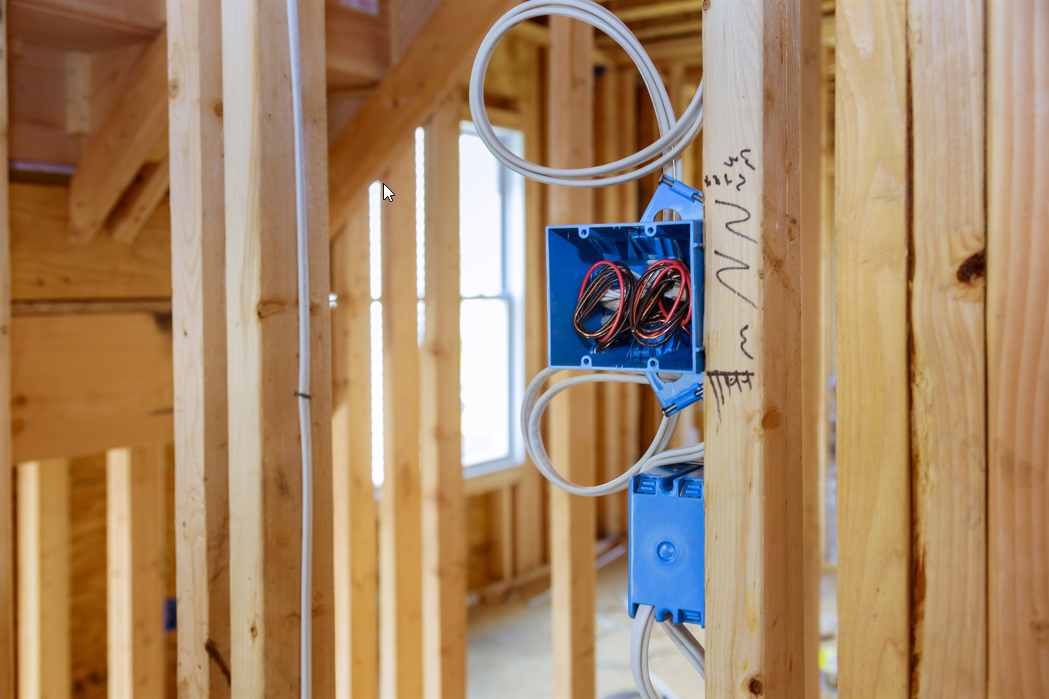 Residential electrical rough-in with blue plastic outlet boxes and NM cable for power distribution and code-compliant wiring.