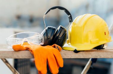 Essential PPE gear including hard hat, gloves, safety glasses, and earmuffs for electrical jobsite protection.