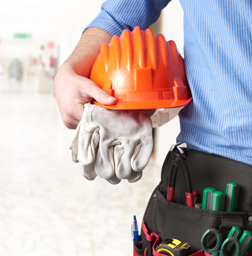 Electrician holding hard hat and gloves with tool belt—ready for on-site electrical work and safety compliance.