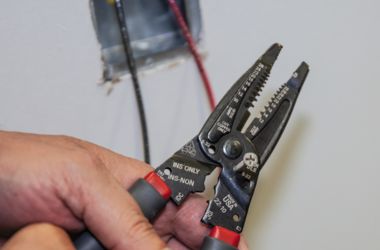 Electrician using wire strippers for precise insulation removal during wiring installation.