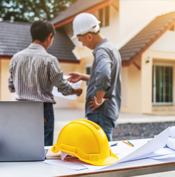 Contractor consultation outside residential jobsite with hard hat and plans—supporting electrical project planning and service questions.